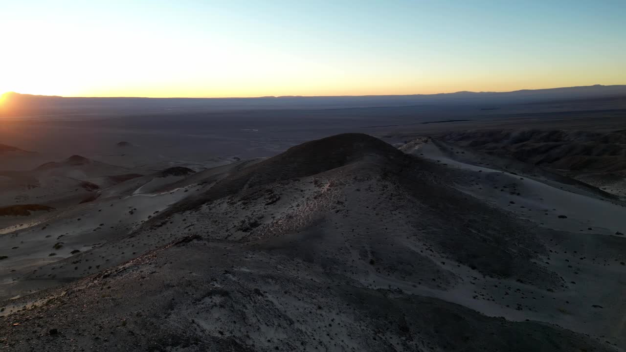Sunset over the barren Atacama mountains, with dramatic ridges glowing in soft golden light