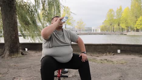 overweight man drinks water while exercising outdoors weight loss concept overweight man drinks water while exercising outdoors weight loss concept