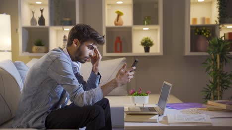 el hombre que envía mensajes de texto en el teléfono en casa por la noche está decepcionado.