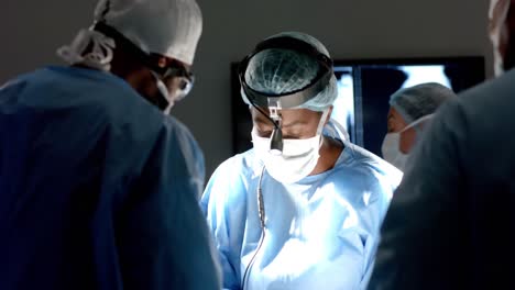 Diverse-surgeons-wearing-surgical-gowns-operating-on-patient-in-operating-theatre,-slow-motion