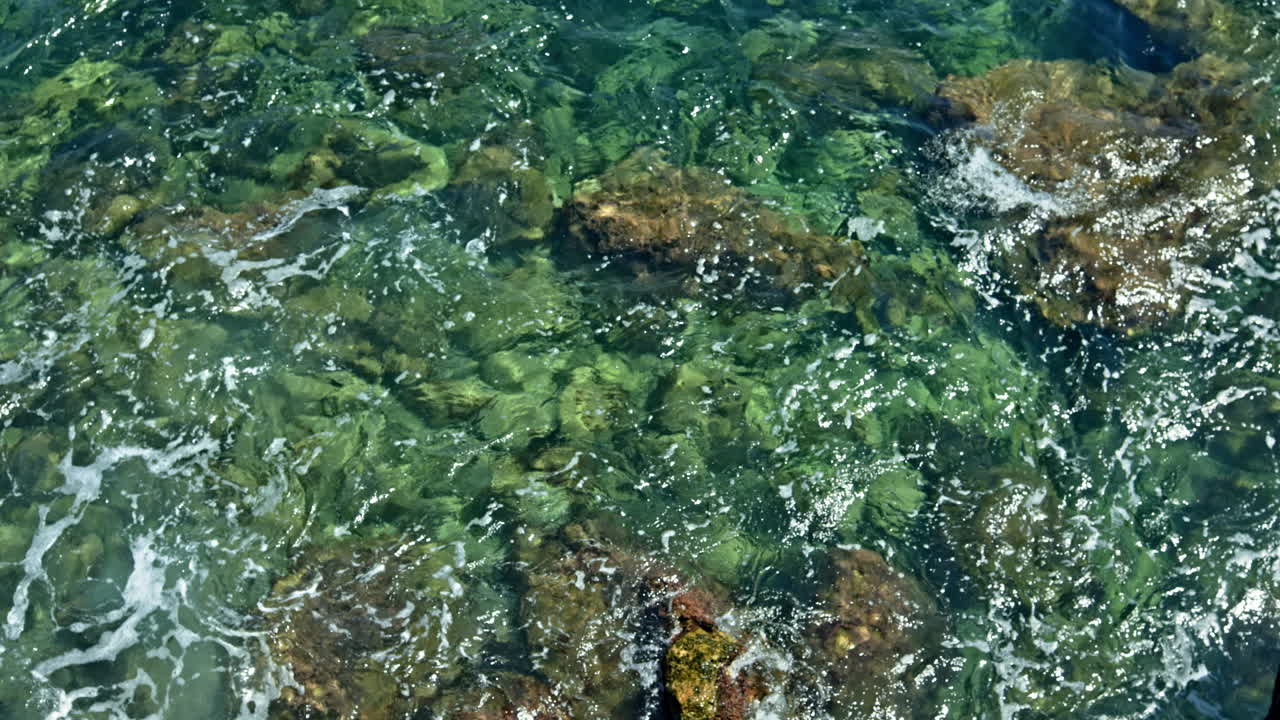 L'oceano con acqua cristallina infrange le onde contro scogliere rocciose. Costa con montagne rocciose. L'acqua di mare forma schiuma colpendo le rocce
