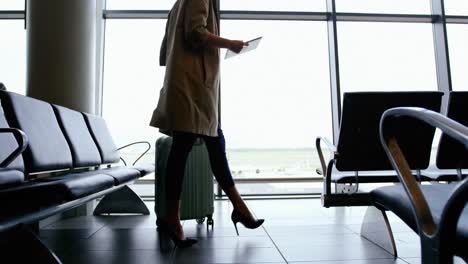 woman holding digital tablet and walking with luggage