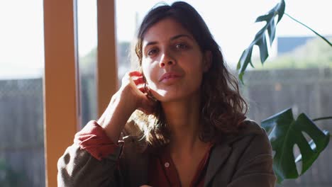 Portrait-of-smiling,-relaxed-mixed-race-woman-sitting-in-sunny-cottage-living-room