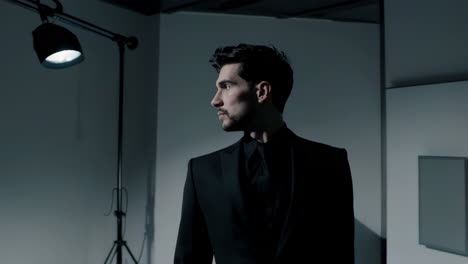 man in a dark suit in a moody studio setting