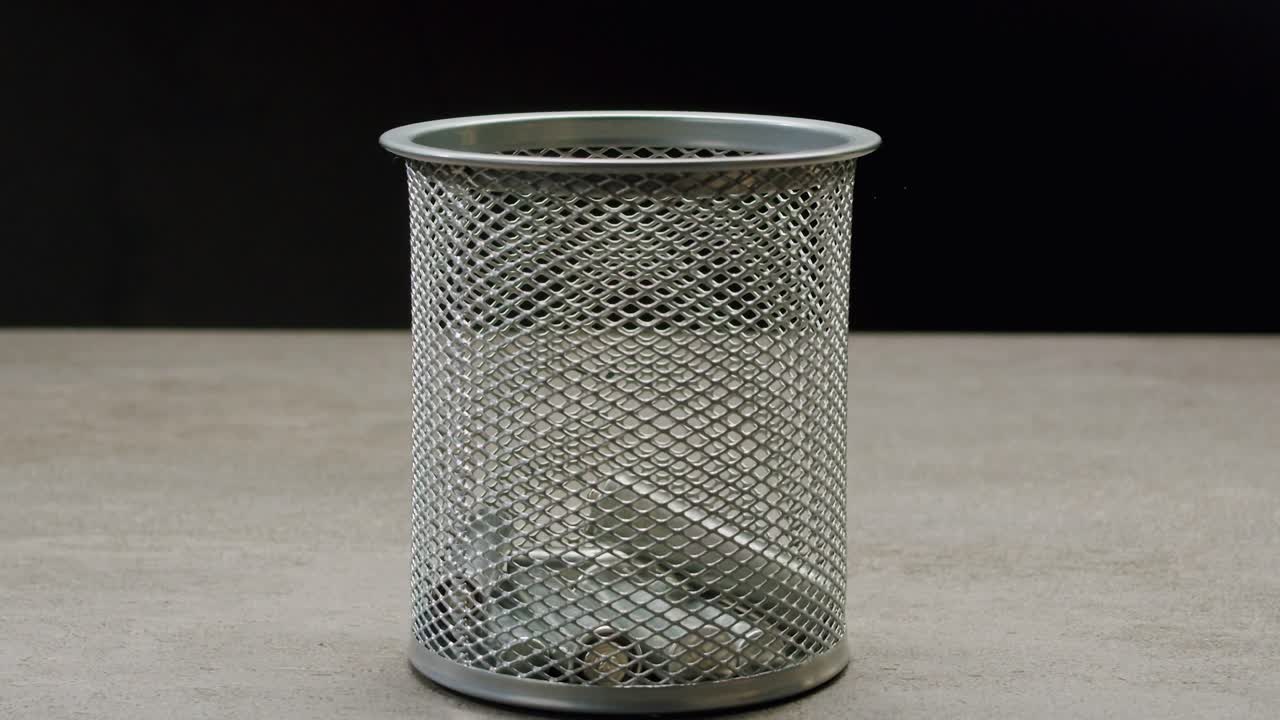 Silver batteries AA and AAA falling into wastebasket close-up. Double-A battery is a standard size single cell cylindrical dry battery. Batteries are common in portable electronic devices. Environmental impacts of lithium-ion batteries concept. An AA battery is composed of a single electrochemical c