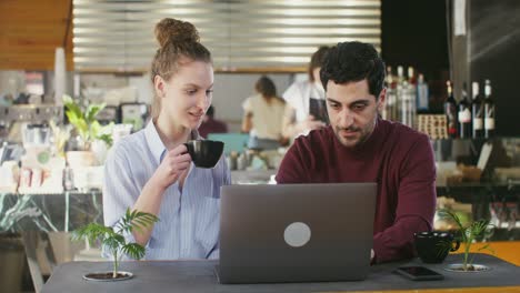 pareja trabajando en una computadora portátil en una cafetería