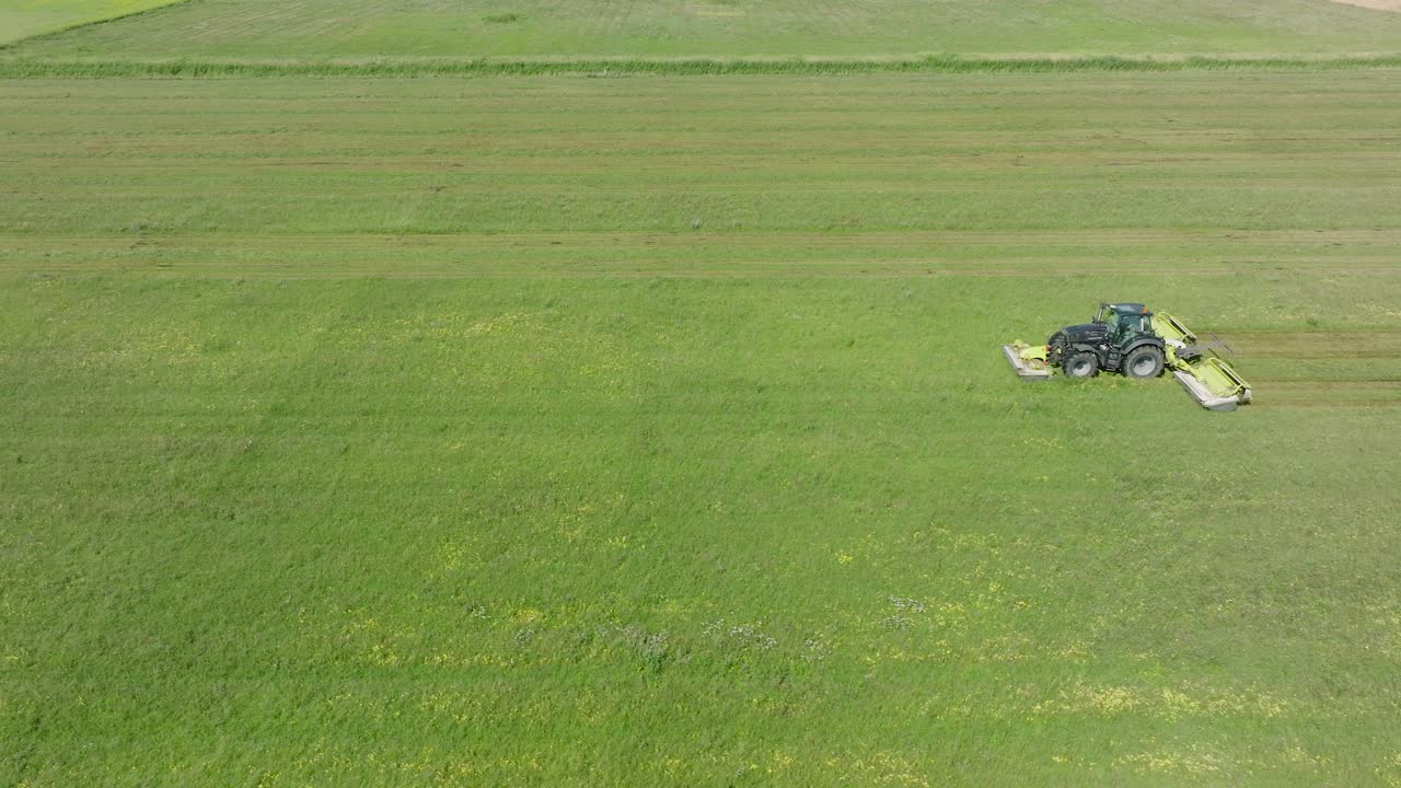 신선한 초록 잔디 ⁇ 을  ⁇ 는 트랙터의 공중 뷰, 현대 트랙터에서 농부 가축을 위한 음식을 준비하는,  ⁇ 은 여름 날, 넓은 드론 돌리  ⁇  왼쪽으로 이동