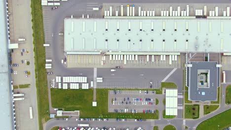 aerial top down view of the big logistics park with warehouses, loading hub and a lot of semi trucks with cargo trailers awaiting for loading unloading goods on ramps