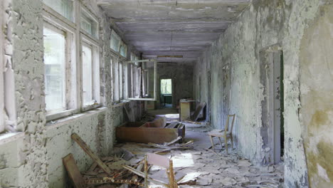 abandoned and empty school hallway with lots of garbage and peeling paint on wall, chernobyl exclusion zone in pripyat, ukraine