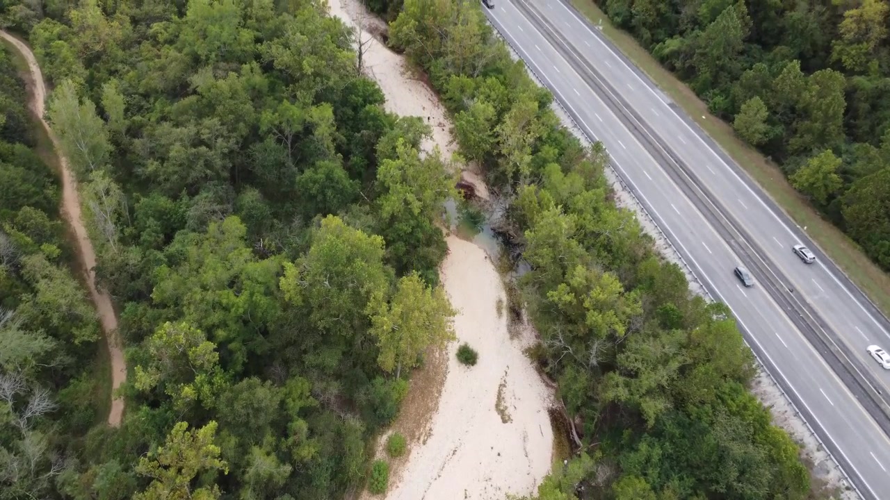Droneoptagelse fra luften, der fanger en stor motorvej, der krydser over en snoet bæk i skovene omkring Busiek State Forest og Wildlife Area i det sydvestlige Missouri