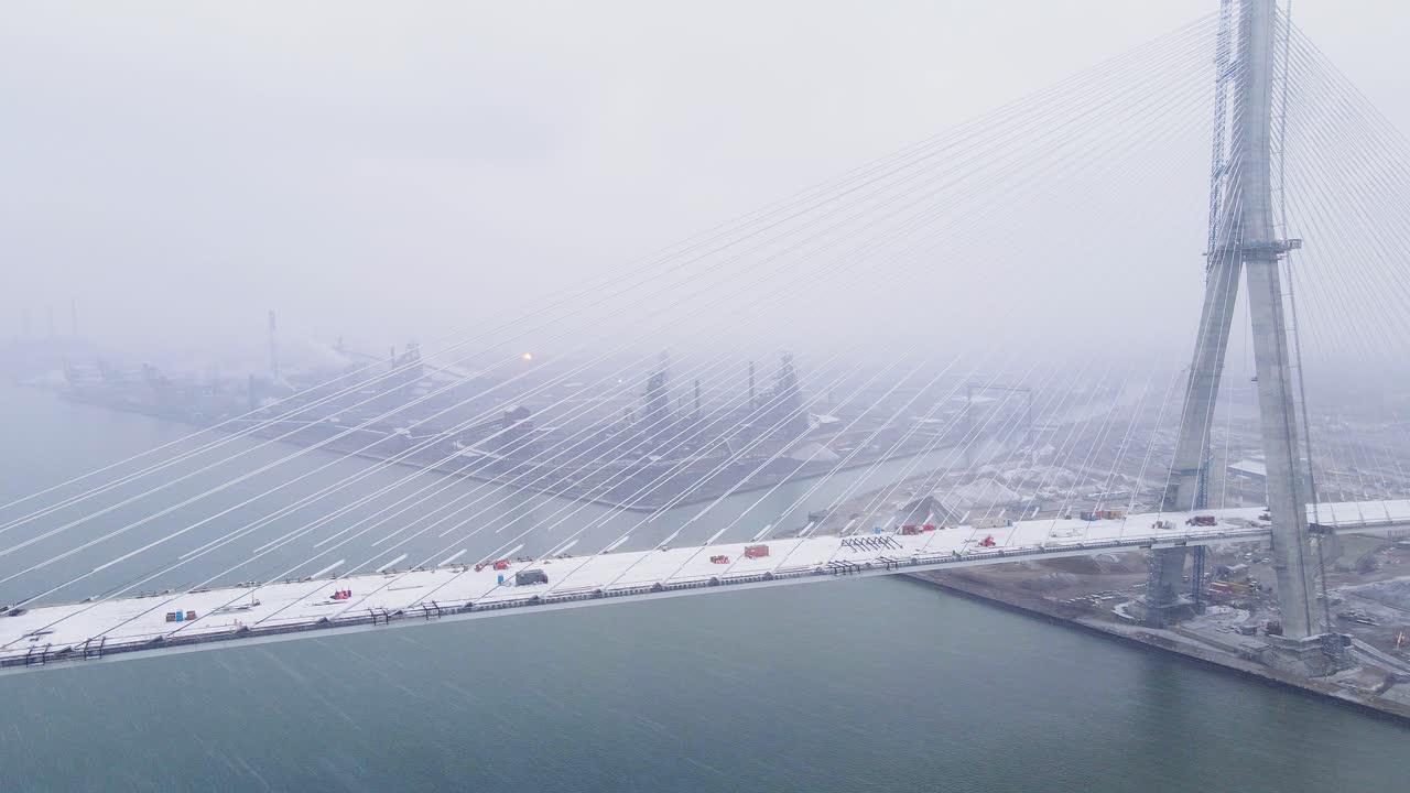 Snowy Gordie Howe Bridge under construction over Detroit River with Detroit Skyline in background