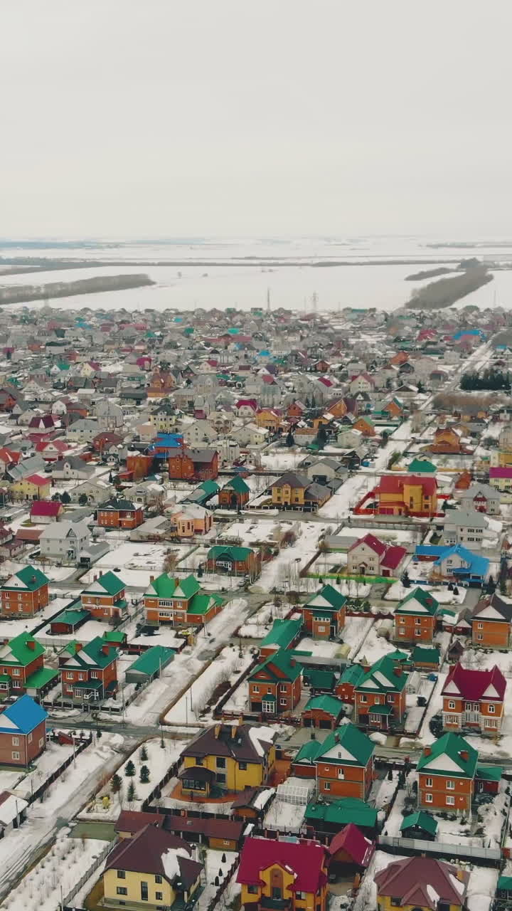 massive cottage complex with colorful houses against distant snowy field and blue sky bird flight view