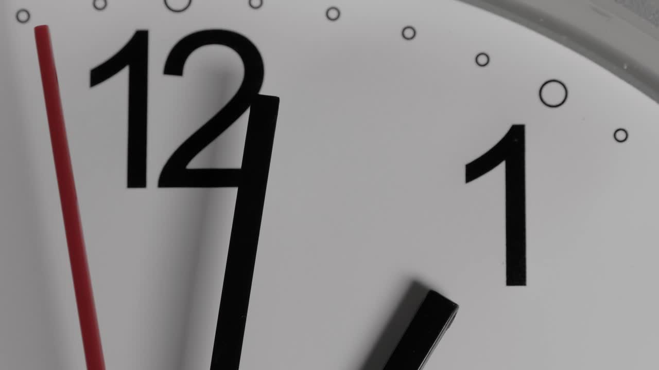 Close-up of a white clock face suggesting the passing of time. Round white clock with black Arabic numerals