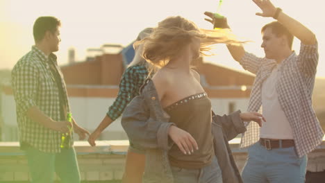 the young american girl is dancing on the roof with her five friends on the party. she smiles and enjoys the time in shorts and a light denim jacket during summer evening.