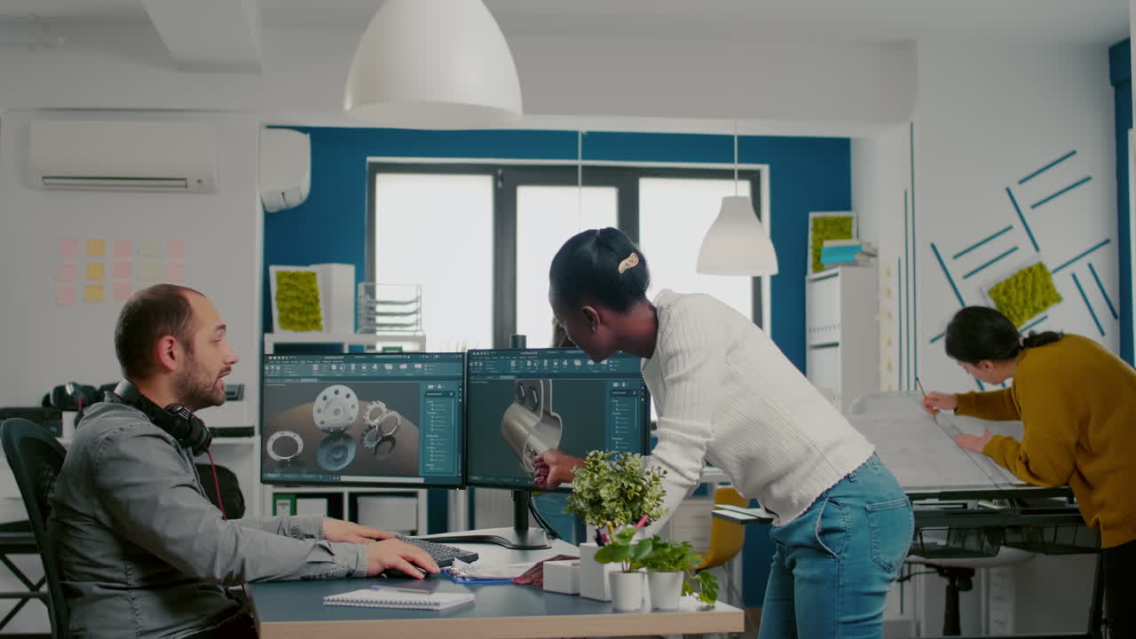 Multiethnic team sharing ideas about industrial project using two monitors