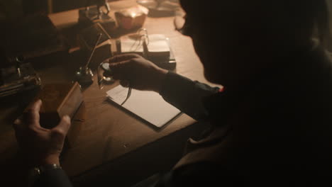 older passionate man evaluates an old watch in his office at night