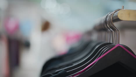 close-up of clothes on hangers in a clothing store with blurred background, focusing on fabric details and vibrant clothing racks, creating a warm, inviting shopping atmosphere