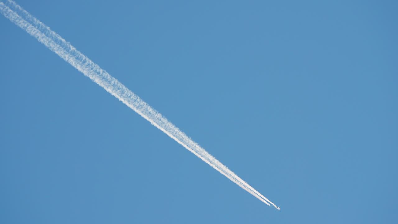Jet Airplane Flying Across Blue Sky Leaving Contrail