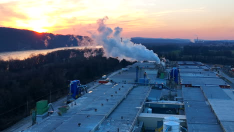 Factory-plant-with-smoke-and-steam-exhaust-during-winter-sunset