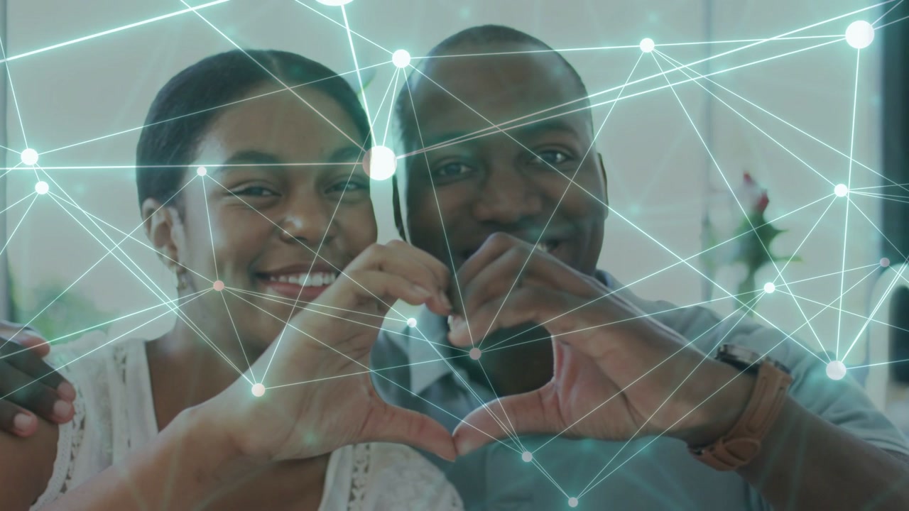 Couple sitting home bringing hands making heart for marketing, net overlay crossing heart and phone