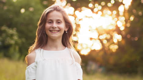 young blonde teen girl walking in summer sunset park looks at camera with alluring look the little