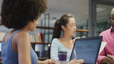 diverse male and female business colleagues talking and using laptop