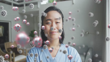 animation of covid 19 cells over smiling asian female doctor