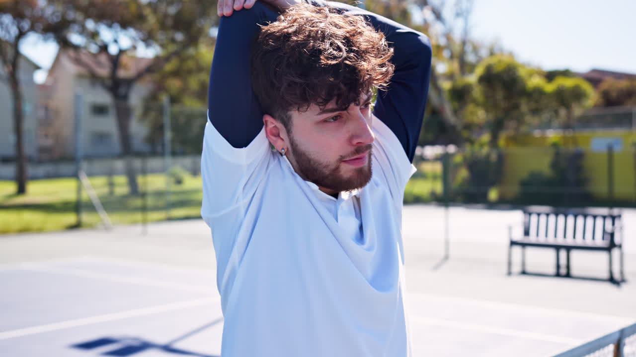 Young Man Stretching Arms on Outdoor Tennis Court