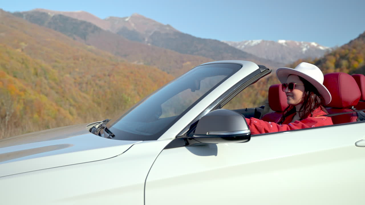 경치 좋은 가을 산 을 가로질러 컨버터블 을 운전 하는 여자