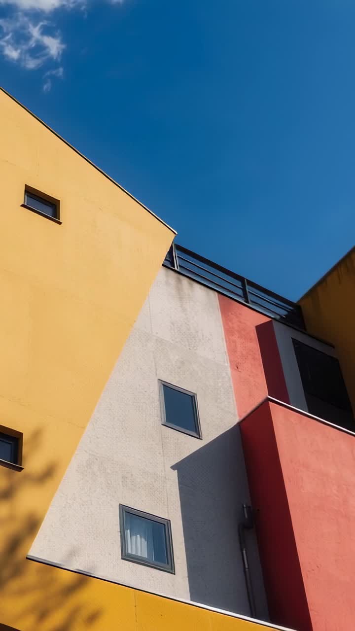 Vertical video: Tilting camera showing colorful walls in alley, revealing windows rail tree shadows