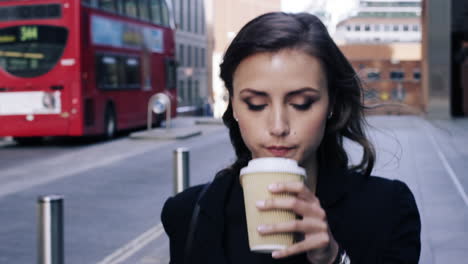 attractive business woman commuter drinking coffee walking in city of london