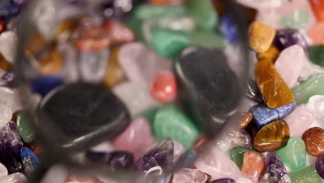 a magnifying glass highlights colorful chakra stones, enhancing their textures and hues under bright lighting