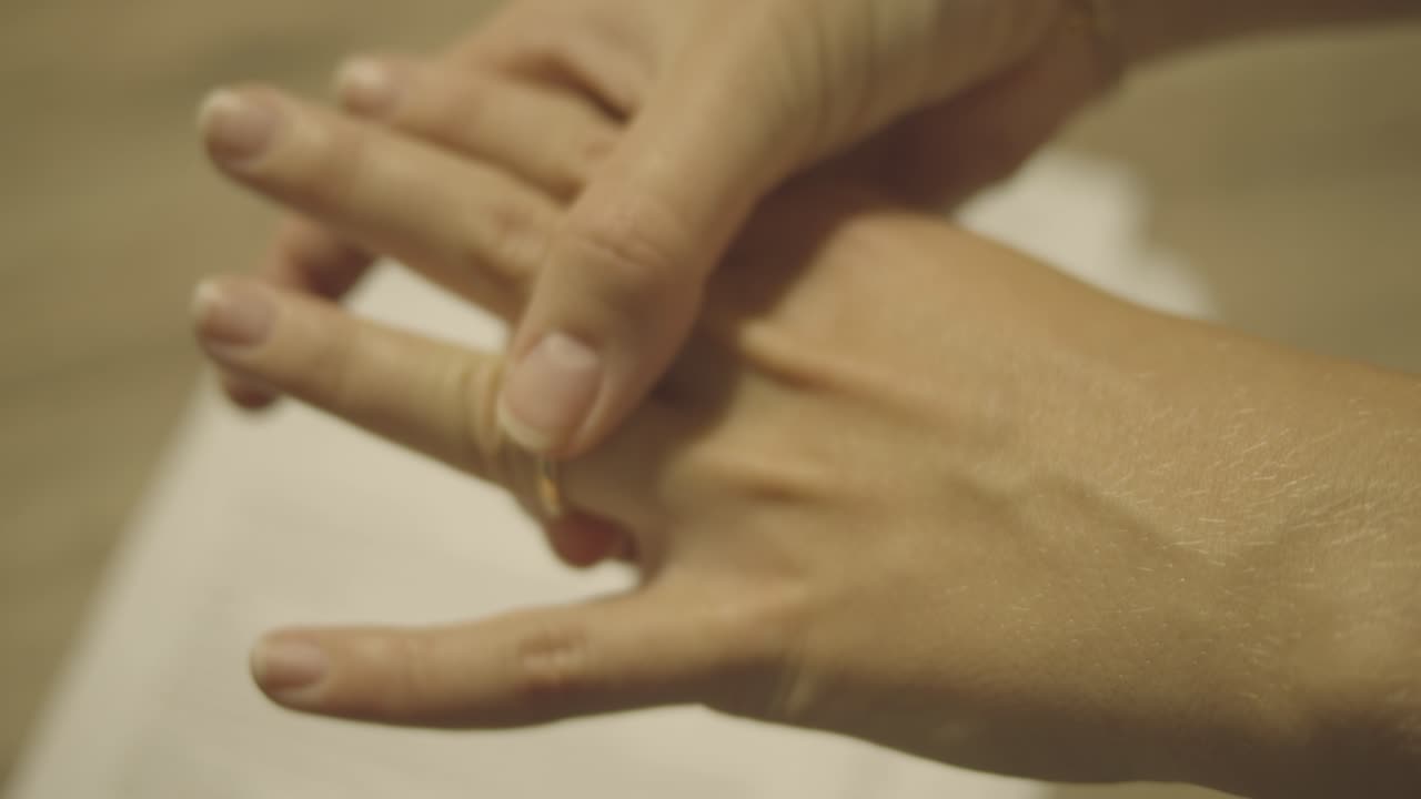 mano femenina - dejando el anillo de bodas en los papeles del divorcio