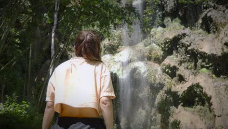 Woman-gazing-at-the-Tumalog-Falls-in-Philippines,-surrounded-by-lush-greenery