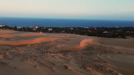 Tourists-exploring-vast-red-sand-dune-landscape-in-Mui-Ne,-Vietnam