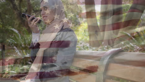 animation of american flag waving over woman in hijab talking on her smartphone