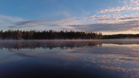 Summer-sunrise-by-beautiful-calm-misty-lake-scenery-in-the-wilderness