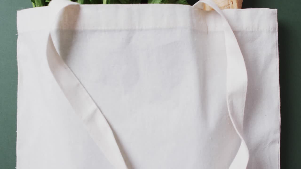 video de una bolsa de lona blanca con perejil, col rizada y baguette, copia espacio en fondo verde