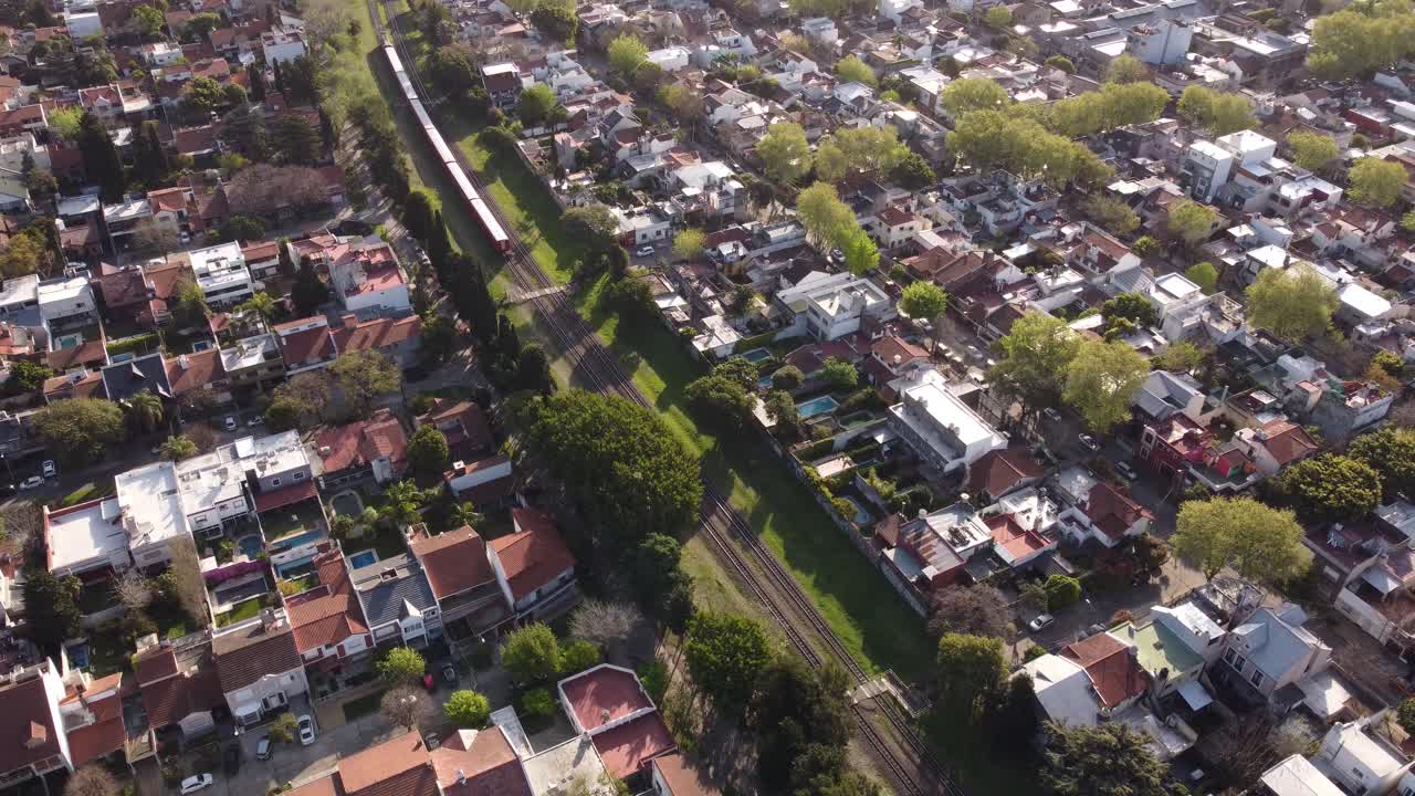 tren rojo cruzando barrio residencial en buenos aires