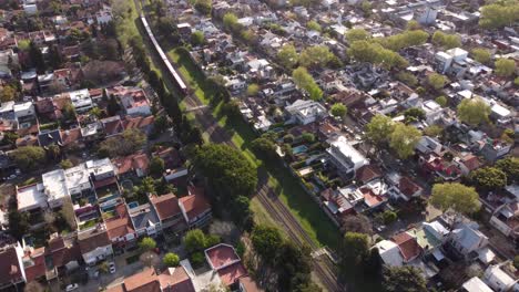 red train crossing residential neighborhood at buenos aires