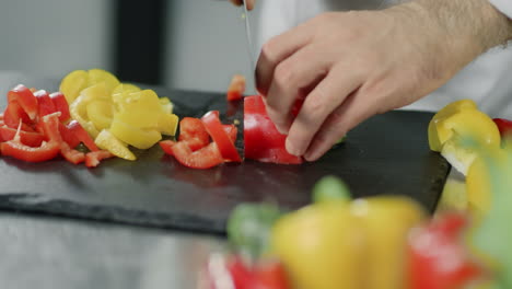 Chef-cooking-healthy-food-at-kitchen-restaurant.-Closeup-hands-cutting-pepper
