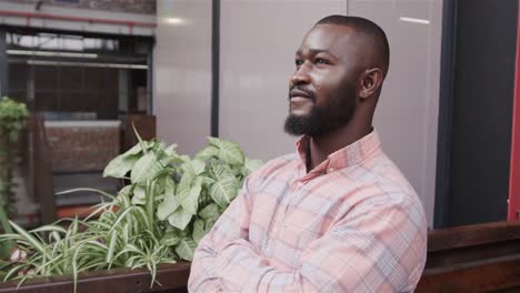 Portrait-of-happy-african-american-casual-businessman-standing-in-office-foyer-smiling,-slow-motion