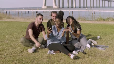 amigos sonrientes mirando el teléfono inteligente mientras posan para una selfie