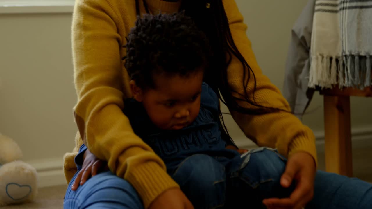 Front view of young black mother playing with her son in a comfortable home 4k