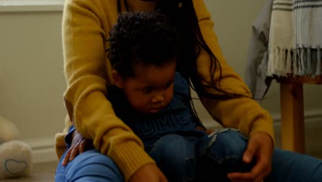 vista frontal de una joven madre negra jugando con su hijo en un cómodo hogar 4k