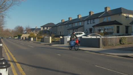 man cycling along quiet road in ireland with grocery bags