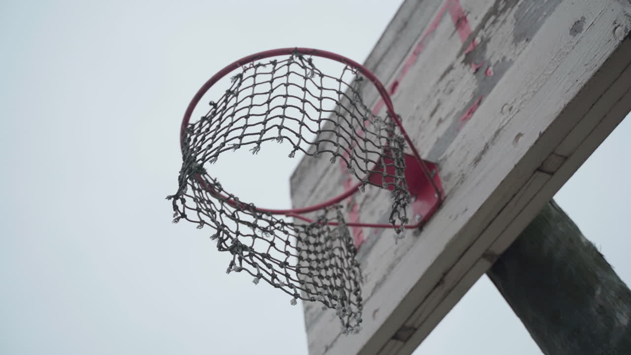 viejo aro de baloncesto con red rota colgando en el viento y pintura pelada