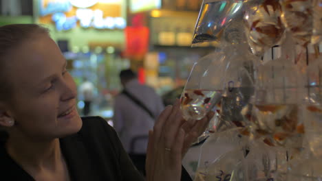 Woman-looking-at-fish-in-street-market-of-Hong-Kong