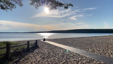 frau macht yoga bei sonnenuntergang über dem strand, sonniger tag, weitwinkel-silhouette an der küste