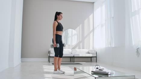 a woman at home on a sunny day in the living room lunges back with dumbbells in her hands. healthy lifestyle daily exercise at home.